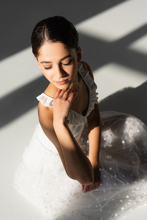 High angle view of young ballerina with closed eyes on grey background