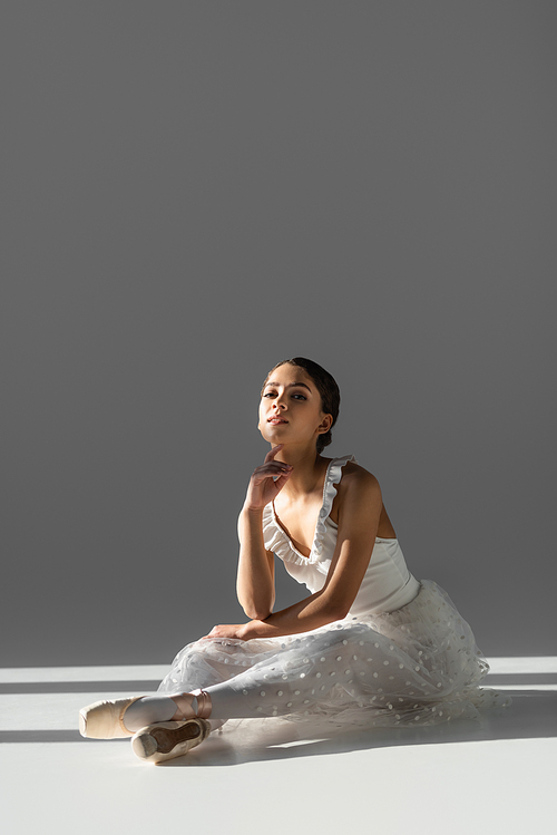 Brunette ballerina  on grey background with sunlight