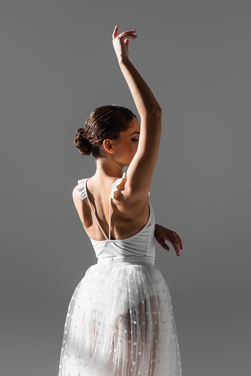 Elegant ballerina raising hand isolated on grey