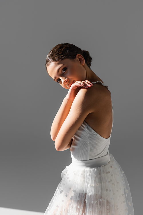 Pretty ballerina  on grey background with sunlight