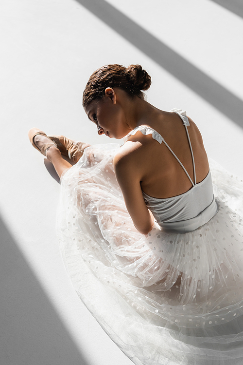 High angle view of ballerina resting on white background with sunlight