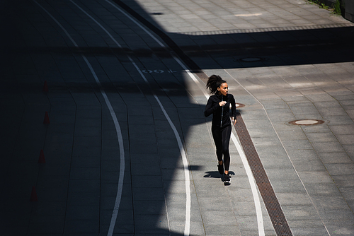 High angle view of african american woman in black sportswear running on track