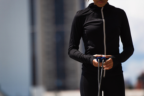 Cropped view of african american sportswoman holding skipping rope outdoors