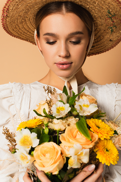 young woman in dress looking at bouquet of flowers on beige