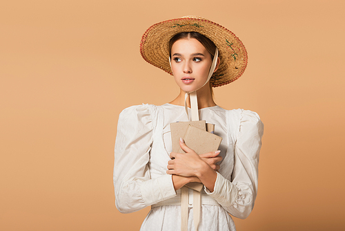 young woman in dress and straw hat holding books on beige