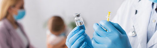 Doctor in latex gloves holding vaccine and syringe near mother and girl on blurred background, banner