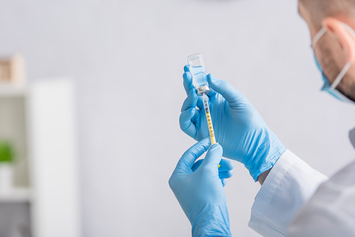 cropped view of doctor in latex gloves filling syringe with vaccine