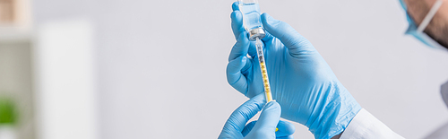 partial view of doctor in blue latex gloves filling syringe with coronavirus vaccine, banner