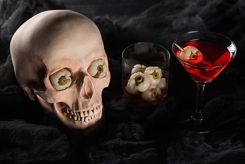 red cocktail near creepy skull on black background