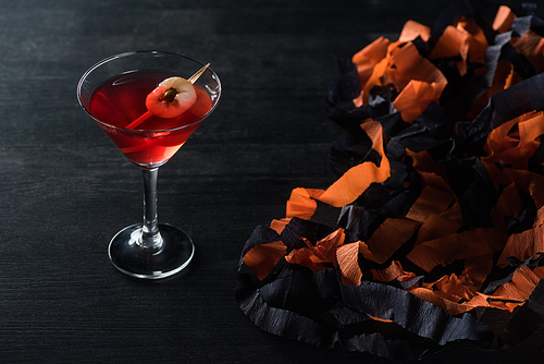 red tasty cocktail near Halloween decoration on black background