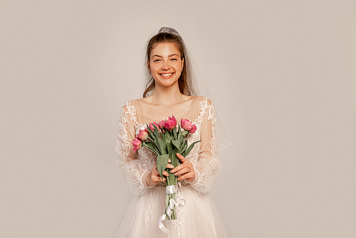 cheerful bride with bouquet of tulips  isolated on grey