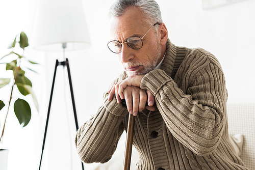 pensive retired man thinking while holding walking stick