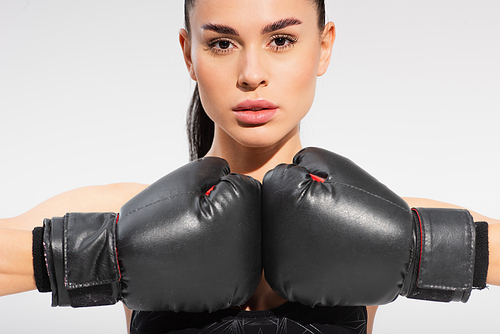 brunette young sportswoman in boxing gloves isolated on grey