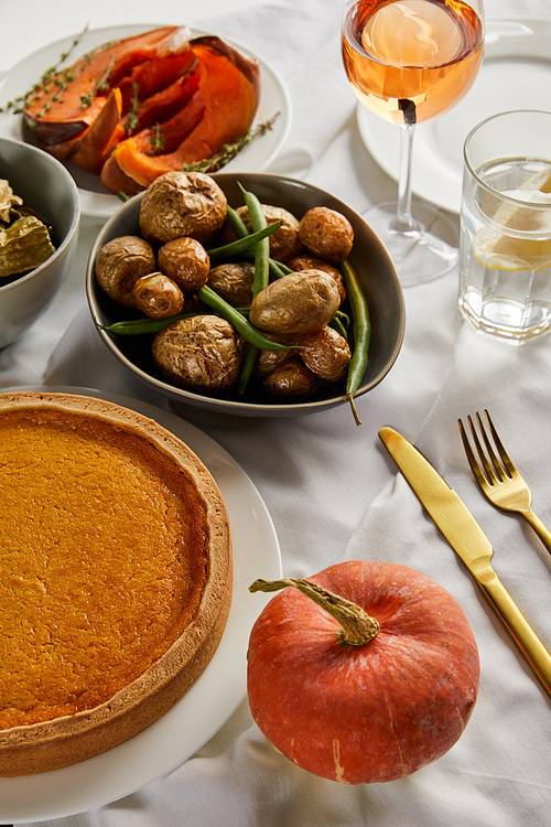 pumkin pie, baked potato and whole pumpkin on white tablecloth isolated on grey