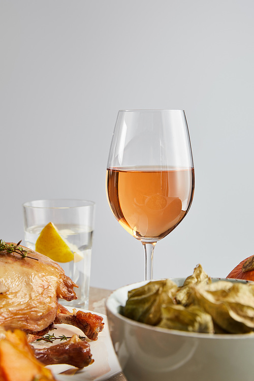 selective focus of glass with rose wine near grilled turkey and backed physalis isolated on grey