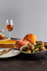 baked pumpkins and potatoes, pumpkin pie and glass with rose wine on wooden table isolated on grey