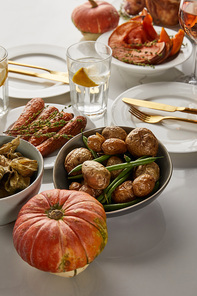festive thanksgiving dinner with grilled vegetables and whole pumpkins served on white marble table