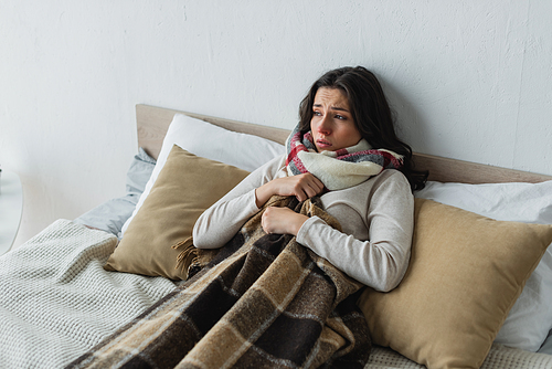 diseased woman lying in bed under checkered blanket at home