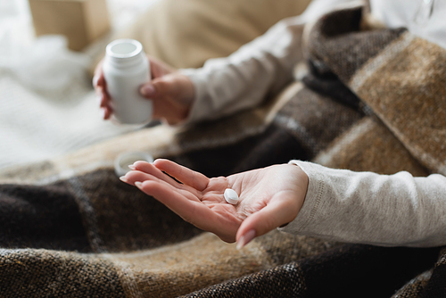 partial view of diseased woman with pill on open palm, blurred background