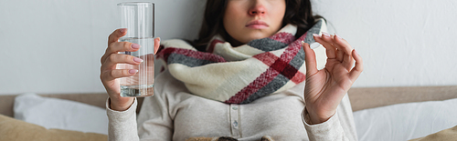 cropped view of sick woman lying in bed with glass of water and pill, banner