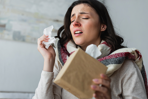 diseased woman holding paper napkins while sneezing with closed eyes