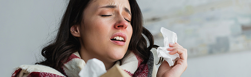 sick woman holding paper napkins while sneezing with closed eyes, banner