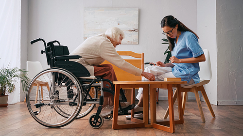 young nurse and happy senior woman playing board game