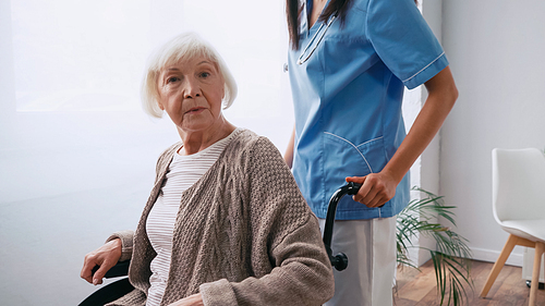 nurse with stethoscope moving aged woman in wheelchair