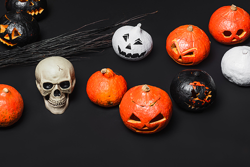 skull near broom and carved pumpkins on black