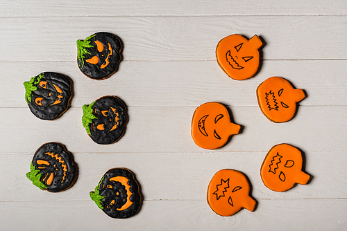 top view of homemade and spooky pumpkin shape halloween cookies on white surface