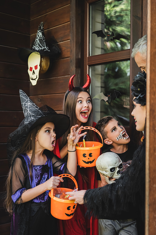 kids in halloween costumes growling at parents on cottage porch with decoration