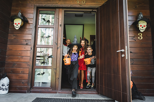 family in spooky costumes running out house with halloween decoration