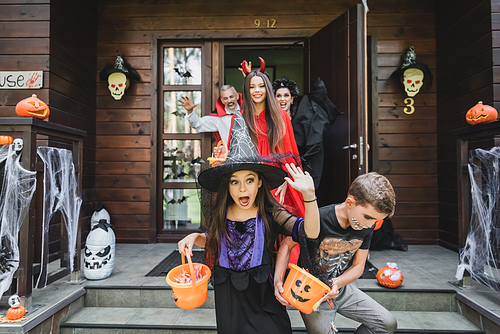 scared girl in halloween costume screaming while running out house from spooky family