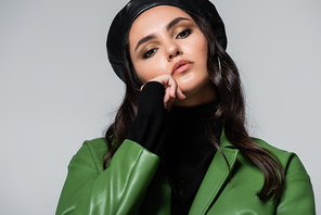 pretty young model in black turtleneck, green jacket and beret  isolated on grey