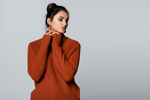 young model in knitted sweater looking away isolated on grey