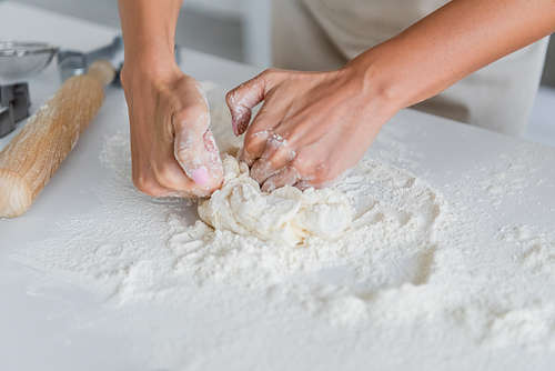 cropped view of woman kneading dough in kitchen