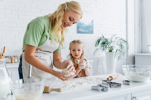 woman and child kneading dough while cooking together in kitchen