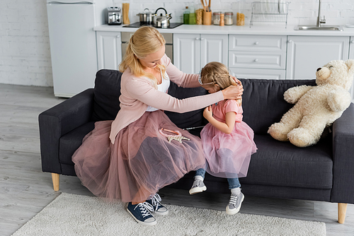 woman in tulle skirt dressing daughter in costume of princess