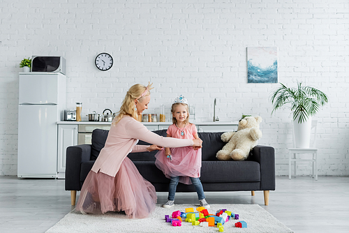 mother and daughter in costumes of princesses playing at home