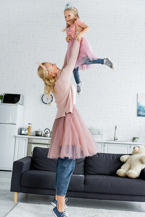 mother in costume of princess holding excited daughter in raised hands