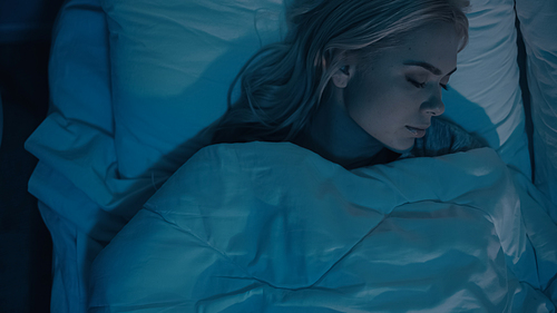 Top view of woman sleeping in white bedding at night