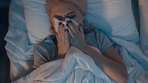 Top view of woman suffering from runny nose on bed
