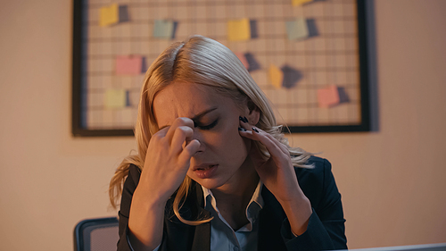 Young businesswoman suffering from headache in office in evening