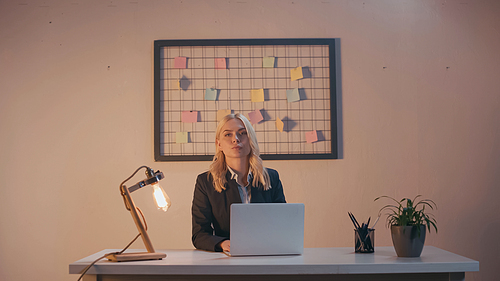 Businesswoman  near laptop and lamp on office table
