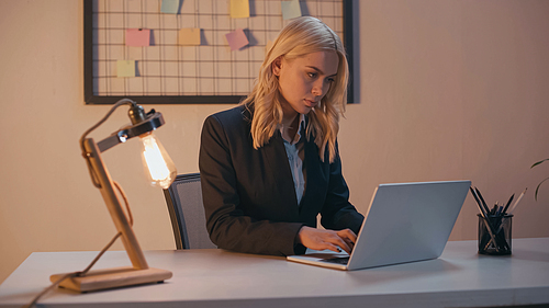 Young businesswoman using laptop while working in office in evening
