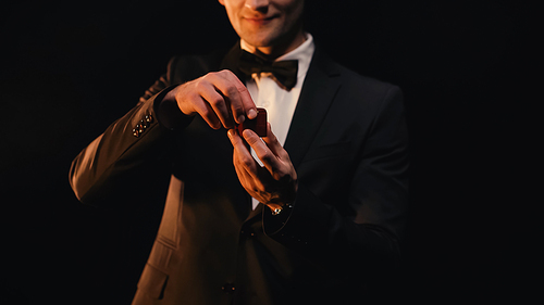 cropped view of man in suit opening red box while making proposal isolated on black