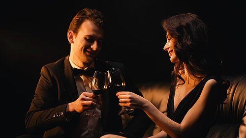 Happy couple clinking glasses of red wine isolated on black