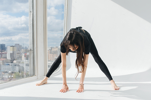 barefoot armenian woman practicing pyramid pose near window