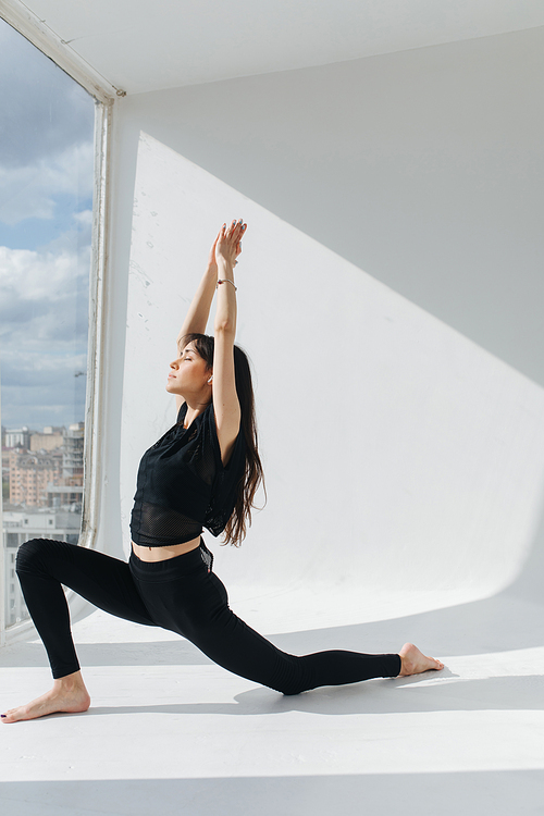 young armenian woman practicing forward lunge pose with raised hands and closed eyes