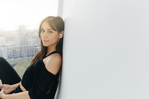 smiling armenian woman in earphone  near white wall